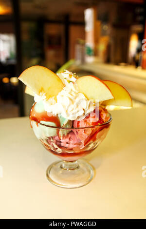 Eisbecher mit Wald Obst und Süßigkeiten schmilzt in ein hohes Becherglas, Nahaufnahme. Handgemachtes Eis Dessert. Eiscafé, Konditorei. Stockfoto