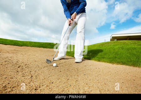 Aktive Menschen in weißen Hosen und blauen pullover stehend auf dem Boden und gehen Golf Ball zu schlagen Stockfoto