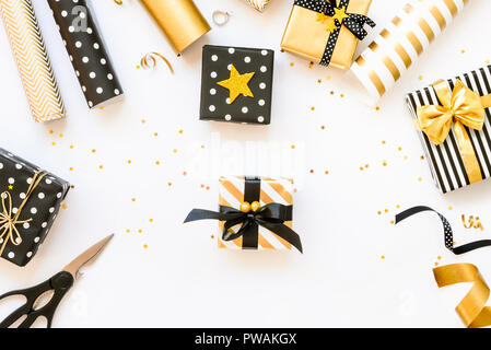 Blick von oben auf die Geschenk Kartons und Verpackungsmaterial in verschiedenen schwarzen, weißen und goldenen Designs. Ein Konzept von Weihnachten, Neujahr, Geburtstag Feier Veranstaltung Stockfoto