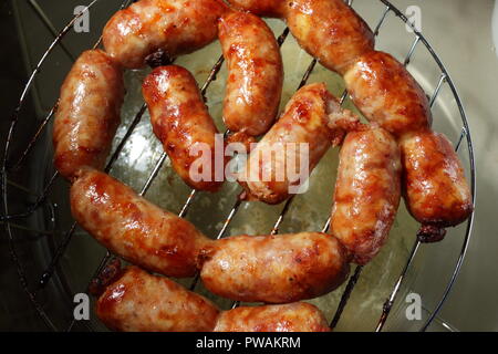 Goldbraune Isanwürste, perfekt gebacken, stehen verführerisch auf einem Backblech. Diese Würstchen sind ein Grundnahrungsmittel der thailändischen Küche. Stockfoto