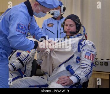 Expedition 57 Flight Engineer Nick Haag der NASA wird unterstützt mit seinem Sokol Klage vor seinem Start einer Sojus-Rakete mit Flugingenieur Alexey Ovchinin von Roskosmos, am Kosmodrom Baikonur 11. Oktober 2018 in Baikonur, Kasachstan. Kurz nach dem Abheben der Rakete versagt auf dem Weg zur Internationalen Raumstation und Abgebrochen zwingt eine Notlandung in Kasachstan. Die Besatzungsmitglieder wurden von Suche und Rettung abgeholt und sind angeblich in gutem Zustand. Stockfoto