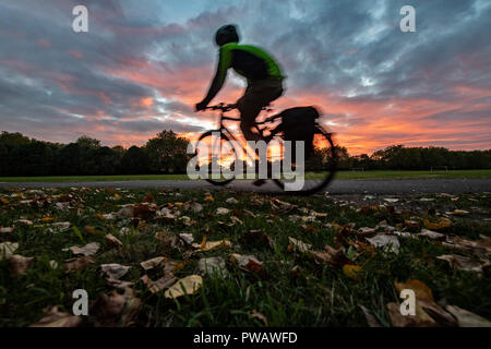 Radfahren in einem dramatischen herbstlicher Sonnenuntergang in einem Londoner Park am Ende des Tages Stockfoto
