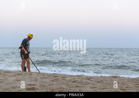 Treasure Hunter mit einem Metalldetektor Spaziergänge am Strand des Schwarzen Meeres nach Sonnenuntergang auf der Suche nach Schatz Stockfoto