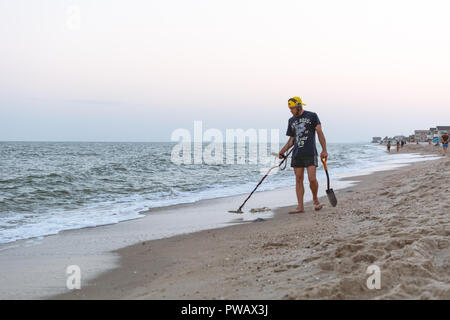 Treasure Hunter mit einem Metalldetektor Spaziergänge am Strand des Schwarzen Meeres nach Sonnenuntergang auf der Suche nach Schatz Stockfoto