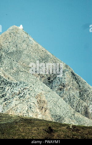 Griechenland, die Insel Anafi. Einen großen Berg dominiert die Landschaft. Auf dem Gipfel ist ein weißes Kapelle thront Stockfoto