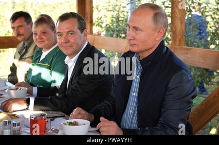 Der russische Präsident Wladimir Putin, rechts, und Ministerpräsident Dimitri Medwedew, Center, melden Sie Landarbeiter zum Mittagessen während einer Tour der Rassvet landwirtschaftliche Firma Oktober 9, 2018 in Georgiyevskaya, Stawropol, Russland. Stockfoto