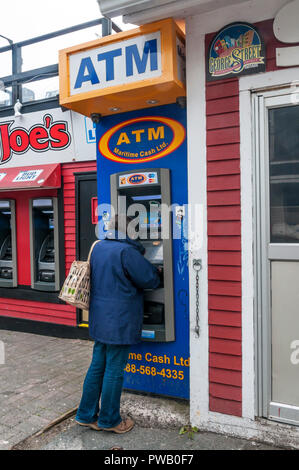 Eine Frau Geld Rückzug aus einem Maritimen Cash Ltd ATM Geldautomaten in St. John's, Neufundland, Kanada. Stockfoto