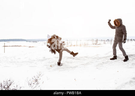 Sorglos glückliches junges Paar gemeinsam Spaß im Schnee im Winter woodland das Werfen mit Schneebällen an jedem anderen während eines mock kämpfen. Stockfoto