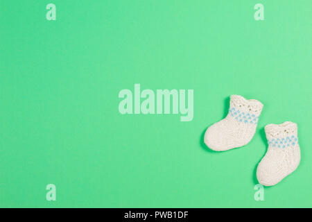 Gestrickte baby Wolle Socken auf grünem Hintergrund Stockfoto
