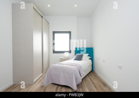 Kleines Schlafzimmer mit einem Einzelbett, einem großen Kleiderschrank und ein Fenster Stockfoto