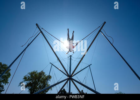 Junge Mädchen im Kabelbaum Springen auf einem Trampolin, während Tethered mit Bungee Kabel Stockfoto