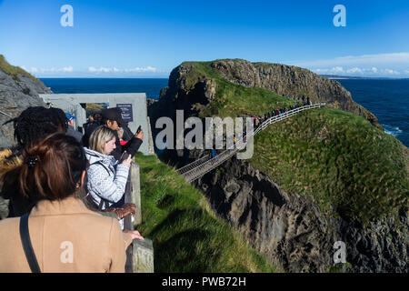 Carrick-a-Rede Rope Bridge, County Antrim, Nordirland, 14. Oktober, 2018. UK Wetter: Warten die Seilbrücke überqueren. Touristen genießen die hellen sonnigen Bedingungen und blauer Himmel bei Carrick-a-Rede Rope Bridge in der Nähe von ballintoy am North Antrim Coast. Die massive Verbesserung der Wetter war nach starkem Regen am Vortag begrüßt. Credit: Ian Proctor/Alamy leben Nachrichten Stockfoto