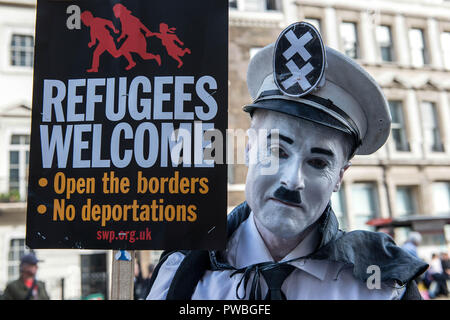 London, Greater London, UK. 13 Okt, 2018. Demonstrant gesehen, Make-up sieht aus wie Hitler und Halten einer antirassistischen Fahne an der antifaschistischen Demonstration gegen die DFLA in London. Gegendemonstration von United gegen Rassismus und Islamophobie, Gewerkschaften organisiert und Stand bis zu Rassismus aus alten Palace Yard zu Whitehall in einem Versuch, die Route der Demokratischen Fußball Jungs Alliance (DFLA) März in London zu Block marschierten. Während der Demonstration gab es Vorfälle, bei denen DFLA Unterstützer versucht, in der Nähe des anti-rassistischen Demonstranten, die Controller erhalten Stockfoto