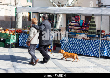 ESPORLES, SPANIEN - 17. FEBRUAR 2018: ein älteres Ehepaar mit Hund wandern entlang der Stände am lokalen Markt in Esporles, Mallorca, Balearen, Spanien Stockfoto