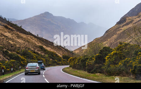 Straße, die in Richtung der fünf Schwestern von Kintail teilweise in Wolken, West Highlands, Schottland, Großbritannien Stockfoto