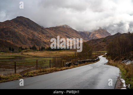 Straße, die in Richtung der fünf Schwestern von Kintail teilweise in Wolken, West Highlands, Schottland, Großbritannien Stockfoto