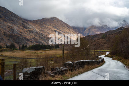 Straße, die in Richtung der fünf Schwestern von Kintail teilweise in Wolken, West Highlands, Schottland, Großbritannien Stockfoto