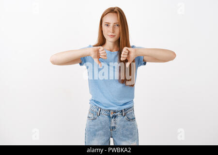 Definitiv nicht. Portrait von unzufrieden und unbeeindruckt gut aussehende bossy Mädchen mit roten Haaren und Sommersprossen runzelte die Stirn und schürzte die Lippen in der Auseinandersetzung mit Daumen nach unten ablehnend schlechte Idee Stockfoto