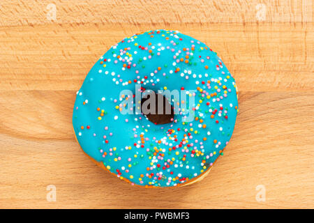 Donut blau mit auf hölzernen Hintergrund isoliert besprüht Stockfoto