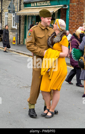 Oktober 2018 ein junger Mann, gekleidet wie eine Armee eine junge Dame im gelben Kleid umfasst bei einer jährlichen Re-enactment in Pickering, North Yorkshire Stockfoto