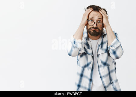 Warum ich. Portrait von umgekippt und düsteren Armen erwachsenen Mann mit Bart und Falten, schürzte die Lippen in trauriges Lächeln und runzelte die Stirn und die Hände auf den Kopf, schlechte Ergebnis der Forschung enttäuscht Stockfoto