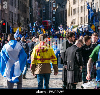 Leute, drapiert mit nationalen Flaggen und Männer in Kilts an Alle unter einem Banner AUOB schottische Unabhängigkeit März 2018, Royal Mile, Edinburgh, Schottland, Großbritannien Stockfoto