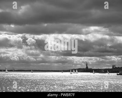 Der Hafen von New York und die Freiheitsstatue an einem grauen frühen Herbsttag, an dem Segelboote den Hudson River fahren. Entfernte Silhouette der Freiheitsstatue. Stockfoto