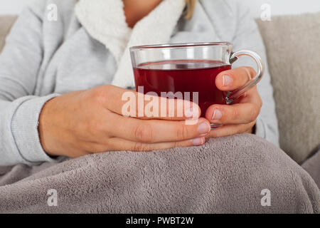 In der Nähe Bild von kranken Frau mit einer Tasse heißen Kaffee beim Sitzen auf der Couch in eine warme Decke gehüllt Stockfoto