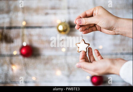 Weibliche Hand, die Weihnachtsdekorationen. Eine sternförmige Keks auf eine Zeichenkette. Kopieren Sie Platz. Stockfoto