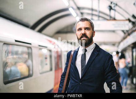 Ernsthafte hipster Geschäftsmann mit einem Beutel warten auf den Zug, in der U-Bahn. Kopieren Sie Platz. Stockfoto