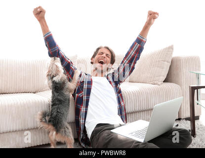Happy Guy frohlockt mit seinem Hund sitzt in der Nähe der Couch im Wohnzimmer. Stockfoto