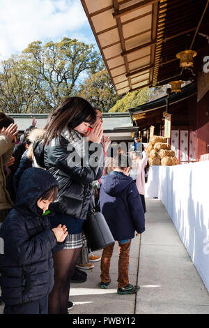 Japanische neues Jahr, shogatsu. Junge Frau und Kind stehen und beten in der Angst, in der Haupthalle, Honden der Nishinomiya Shinto Schrein. Stockfoto