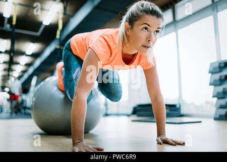 Junge attraktive Frau, Push-ups mit Kugel Stockfoto