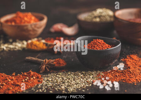 Verschiedene Gewürze in Holzschalen auf dunklem Hintergrund. Essen Hintergrund. Stockfoto
