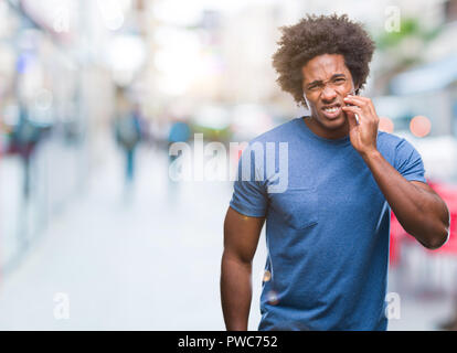 Afro-amerikanische Mann über isolierte Hintergrund berühren den Mund mit der Hand mit schmerzhaften Ausdruck wegen Zahnschmerzen oder zahnmedizinische Krankheit auf die Zähne. Zahnarzt c Stockfoto