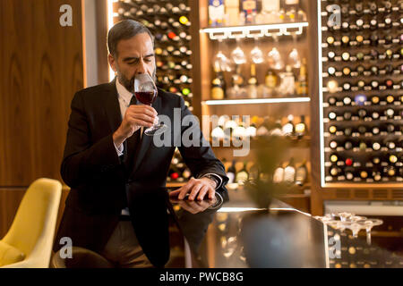 Portrait von älteren gutaussehenden Mann trinken Rotwein Stockfoto