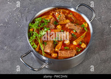 Herzhaftes Rindfleisch und Okra Eintopf in eine Kasserolle auf einer konkreten Tabelle, Ansicht von oben, close-up Stockfoto