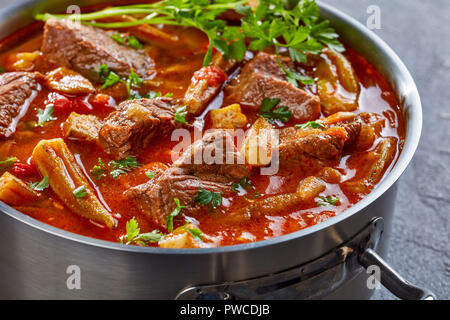 Überblick über herzhaftes Rindfleisch und Okra Eintopf in eine Kasserolle auf einer konkreten Tabelle, Ansicht von oben, close-up Stockfoto