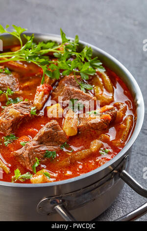 Überblick über herzhaftes Rindfleisch und Okra Eintopf in eine Kasserolle auf einer konkreten Tabelle, vertikale Ansicht von oben, close-up Stockfoto