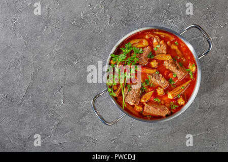 Überblick über herzhaftes Rindfleisch und Okra Suppe in eine Kasserolle auf einer konkreten Tabelle, Ansicht von oben, flach Stockfoto