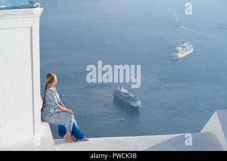 Glückliche Frau in weißen und blauen Dress ihr Urlaub auf Santorini, Griechenland genießen. Blick auf Caldera und die Ägäis von Imerovigli. Stockfoto