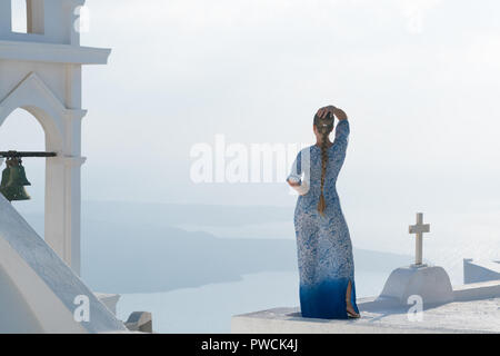 Glückliche Frau in weißen und blauen Dress ihr Urlaub auf Santorini, Griechenland genießen. Blick auf Caldera und die Ägäis von Imerovigli. Stockfoto