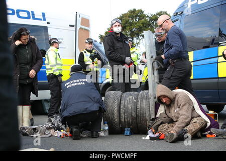 Ein Polizeiteam schneidet einen Mann und eine Frau aus einem Satz Reifen, die sie anscheinend mit ihren Armen auf dem Gelände des Energieunternehmens Cuadrilla in Preston New Road, Little Plumpton, in der Nähe von Blackpool eingekert hatten. Fracking-Demonstranten haben gesagt, dass ihr Kampf gerade „ernst“ wurde, da der umstrittene Prozess in Lancashire beginnen soll. Stockfoto