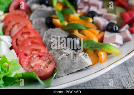 Ein beliebtes Gericht der amerikanischen Küche - Cobb Salat, bestehend aus grünen, Eier, Tomaten, Käse, Fleischwaren, in Reihen gestapelt auf eine große Schüssel und poure Stockfoto