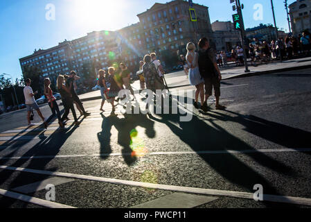 Russland, Moskau - 10. Juli 2018: Anonyme Leute mit langen Schatten auf Zebrastreifen Stockfoto