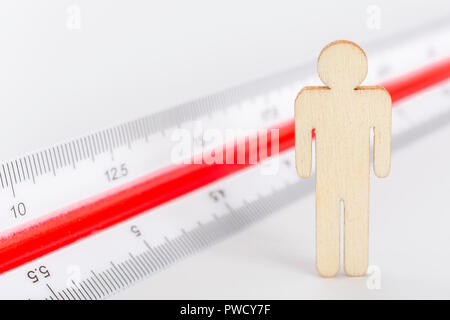 Makro kleine Laser-cut Holzfigur und Lineal. Metapher Messen persönliche Leistung, Demographie Konzept, Produktivität, die Maßnahme von einem Mann bekommen. Stockfoto