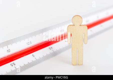Makro kleine Laser-cut Holzfigur und Lineal. Metapher Messen persönliche Leistung, Demographie Konzept, Produktivität, die Maßnahme von einem Mann bekommen. Stockfoto