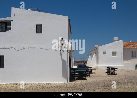 Weiße Wände der Gebäude und einen roten Dachziegel vom Dach. Gepflasterter Platz mit Kopfsteinpflaster. Laterne an der Ecke, die Schatten der Kabel. Leere Tabellen einer Stockfoto