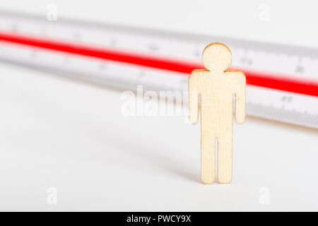 Makro kleine Laser-cut Holzfigur und Lineal. Metapher Messen persönliche Leistung, Demographie Konzept, Produktivität, die Maßnahme von einem Mann bekommen. Stockfoto