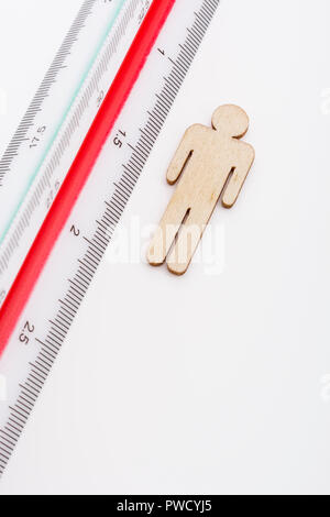 Makro kleine Laser-cut Holzfigur und Lineal. Metapher Messen persönliche Leistung, Demographie Konzept, Produktivität, die Maßnahme von einem Mann bekommen. Stockfoto